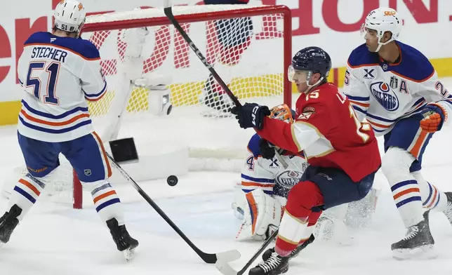 Florida Panthers' Anton Lundell (15) scores against Edmonton Oilers goalie Stuart Skinner, second from left, as Oilers' Darnell Nurse (25) and Troy Stecher (51) look on during the first period in Game 4 of the NHL hockey Stanley Cup Final in Sunrise, Fla., Thursday, June 12, 2025. (Nathan Denette/The Canadian Press via AP)