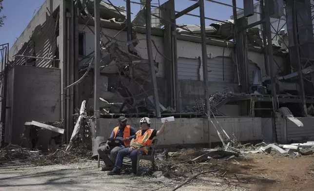 Workers sit next to a building at the Weizmann Institute of Science destroyed by an Iranian missile in Rehovot, Thursday, June 19, 2025. (AP Photo/Maya Alleruzzo)