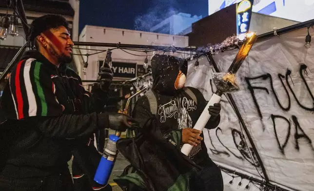 Protesters prepare to launch projectiles during protests over the Trump administration's immigration raids in Los Angeles, Monday, June 9, 2025. (AP Photo/Ethan Swope)