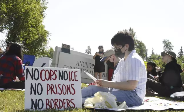 Demonstrators sit on the lawn of the Anchorage Correctional Complex Thursday, June 12, 2025, in Anchorage, Alaska, to protest the detainment of about 40 people being held there under the custody of the Immigration and Customs Enforcement federal agency. (AP Photo/Mark Thiessen)