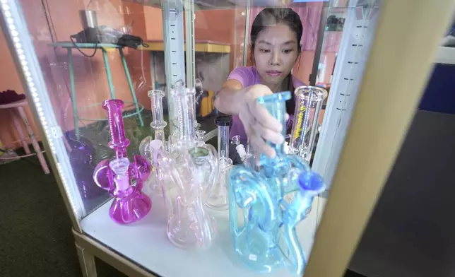 A staff arranges bongs at a cannabis shop after Thailand started banning the sale of cannabis to those without a prescription in Bangkok, Thailand, Friday, June 27, 2025. (AP Photo/Sakchai Lalit)