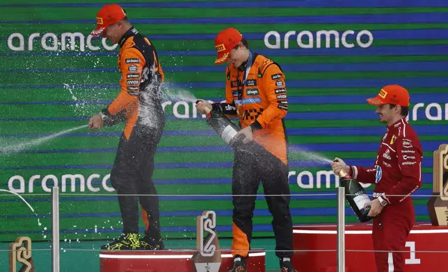 McLaren driver Oscar Piastri of Australia, center, celebrates on the podium with McLaren driver Lando Norris of Britain, left, and Ferrari driver Charles Leclerc of Monaco after winning the Spanish Grand Prix Formula One race at the Barcelona Catalunya racetrack in Montmelo, near Barcelona, Spain, Sunday, June 1, 2025. (AP Photo/Joan Monfort)