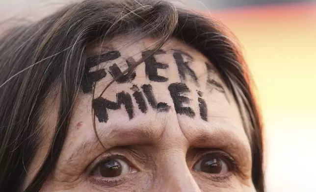 The forehead of a supporter of Argentina's former President Cristina Fernandez reads in Spanish: "Milei out," referring to current President Javier Milei, during a march in support of Fernandez, who has begun serving a six-year prison sentence under house arrest for corruption, in Buenos Aires, Argentina, Wednesday, June 18, 2025. (AP Photo/Gustavo Garello)