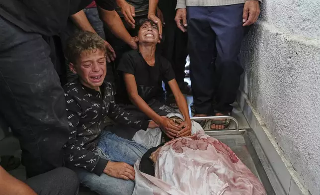 Palestinians children mourn over the body of their father, Mohammed Ghaben, who was killed while heading to an aid distribution hub, at the morgue of the Shifa Hospital in Gaza City, Wednesday, June 18, 2025. (AP Photo/Jehad Alshrafi)