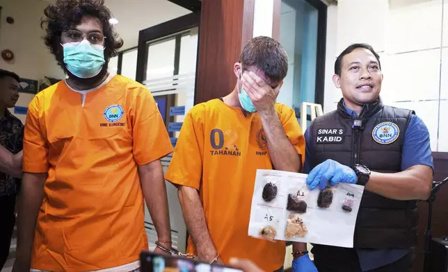 Australian national identified only as P.R., center, and an Indian national identified as H.V., left, who were arrested for drug possession, react as a National Narcotics Agency officer shows evidence confiscated from them, during a press conference in Denpasar, Bali, Indonesia Thursday, June 5, 2025. (AP Photo/Firdia Lisnawati)