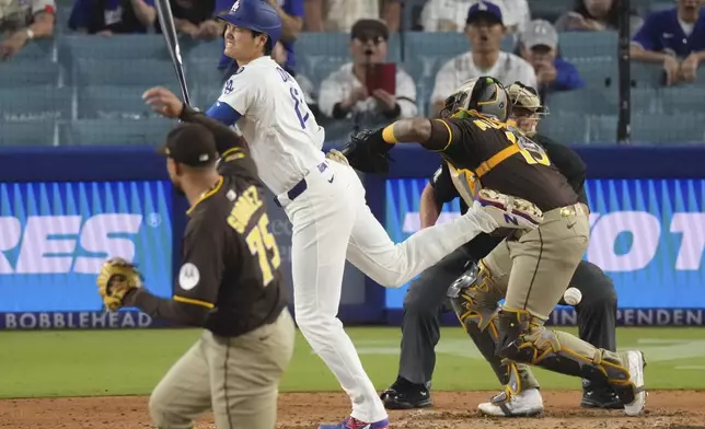 Los Angeles Dodgers' Shohei Ohtani, center is hit by a pitch thrown by San Diego Padres relief pitcher Robert Suarez, left as catcher Martin Maldonado watches during the ninth inning of a baseball game Thursday, June 19, 2025, in Los Angeles. (AP Photo/Mark J. Terrill)