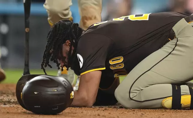 San Diego Padres' Fernando Tatis Jr. kneels on the ground after being hit by a pitch during the ninth inning of a baseball game against the Los Angeles Dodgers, Thursday, June 19, 2025, in Los Angeles. (AP Photo/Mark J. Terrill)