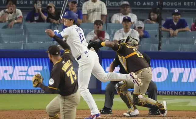 Los Angeles Dodgers' Shohei Ohtani, center is hit by a pitch thrown by San Diego Padres relief pitcher Robert Suarez, left as catcher Martin Maldonado watches during the ninth inning of a baseball game Thursday, June 19, 2025, in Los Angeles. (AP Photo/Mark J. Terrill)