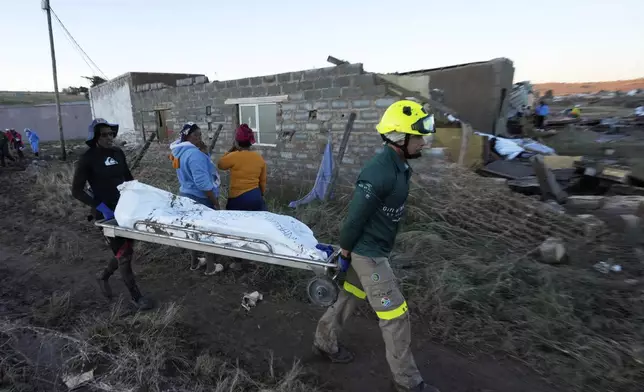 Rescue workers transport a person in a body bag after floods swept through the area in Mthatha, South Africa, Thursday, June 12, 2025. (AP Photo/Themba Hadebe)