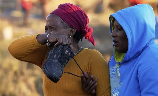 A relative reacts as bodies of her sister and three daughters were retrieved from inside a one room house, after floods swept through the area in Mthatha, South Africa, Thursday, June 12, 2025. (AP Photo/Themba Hadebe)