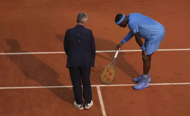 United States' Frances Tiafoe and the chair umpire check the mark on the clay as he plays against Italy's Lorenzo Musetti during their quarterfinal match of the French Tennis Open at the Roland-Garros stadium in Paris, Tuesday, June 3, 2025. (AP Photo/Thibault Camus)