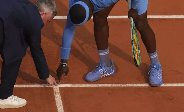 United States' Frances Tiafoe and the chair umpire check the mark on the clay as he plays against Italy's Lorenzo Musetti during their quarterfinal match of the French Tennis Open at the Roland-Garros stadium in Paris, Tuesday, June 3, 2025. (AP Photo/Thibault Camus)