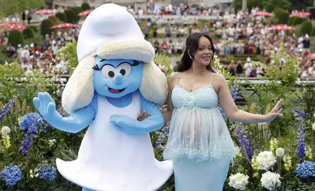Rihanna poses with a person in a Smurfette costume for photographers upon arrival at the world premiere of the film "Smurfs", on Saturday, June 28, 2025, in Brussels. (AP Photo/Omar Havana).