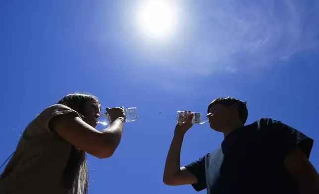 FILE - Tony Berastegui Jr., right, and his sister Giselle Berastegui drink water, July 17, 2023, in Phoenix. (AP Photo/Ross D. Franklin, File)