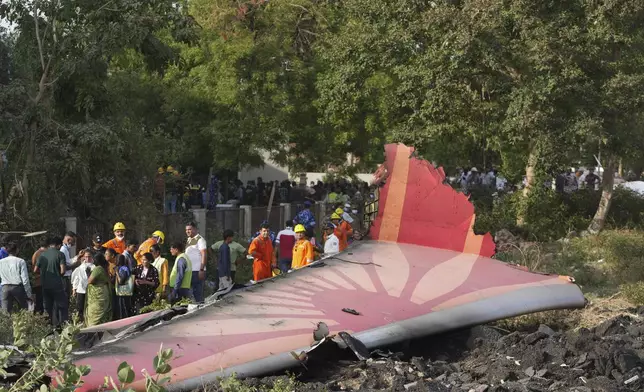 People stand around the debris of an airplane after it crashed in India's northwestern city of Ahmedabad in Gujarat state, Thursday, June 12, 2025. (AP Photo/Ajit Solanki)