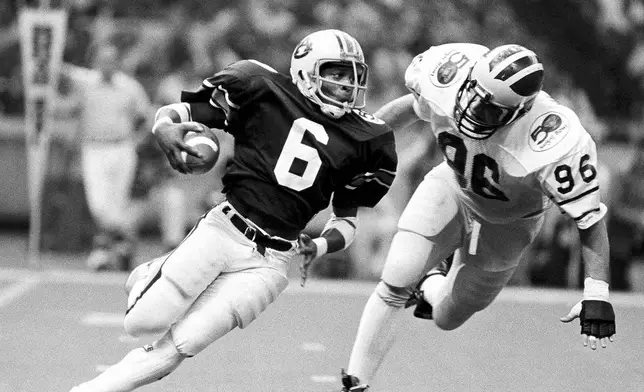 FILE - Auburn's Lionel James, (6) gains yardage as Michigan's Dave Meredith (96) tries to stop him in NCAA college football Sugar Bowl action in New Orleans, Jan. 2, 1984. (AP Photo, file)