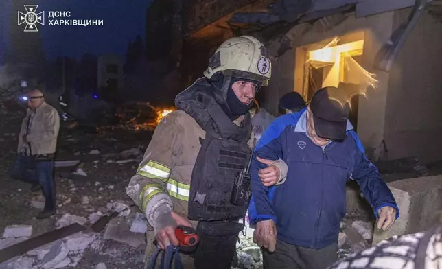 In this photo provided by the Ukrainian Emergency Services on Thursday, June 12, 2025, a rescue worker evacuates a man from a building which was damaged by a Russian strike in Kharkiv, Ukraine. (Ukrainian Emergency Services via AP)