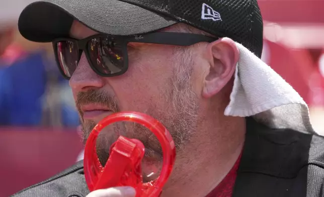 Travis Law uses a portable fan as he tries to stay cool in Busch Stadium before the start of a baseball game between the St. Louis Cardinals and the Cincinnati Reds Saturday, June 21, 2025, in St. Louis. (AP Photo/Jeff Roberson)