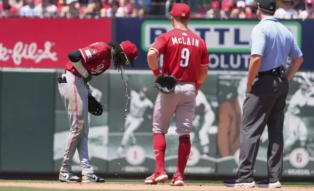 Cincinnati Reds shortstop Elly De La Cruz, left, becomes sick on the field as teammate Matt McLain (9) and second base umpire Adam Beck, right, watch during the fourth inning of a baseball game against the St. Louis Cardinals Saturday, June 21, 2025, in St. Louis. (AP Photo/Jeff Roberson)