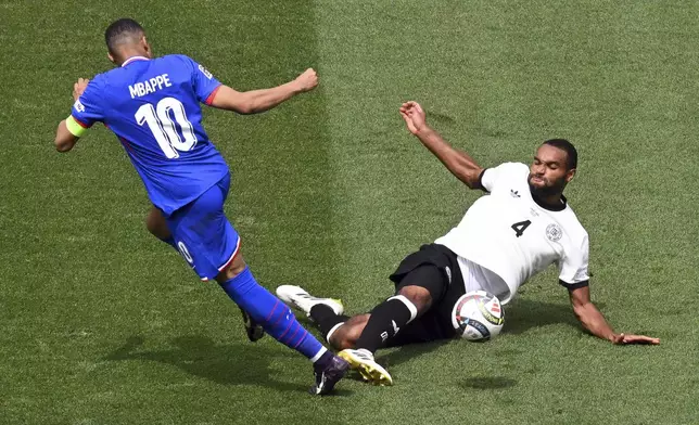 France's Kylian Mbappe, left, and Germany's Jonathan Tah, right, challenge for the ball during the Nations League third place soccer match between Germany and France in Stuttgart, Germany, Sunday, June 8, 2025. (Marijan Murat/dpa via AP)