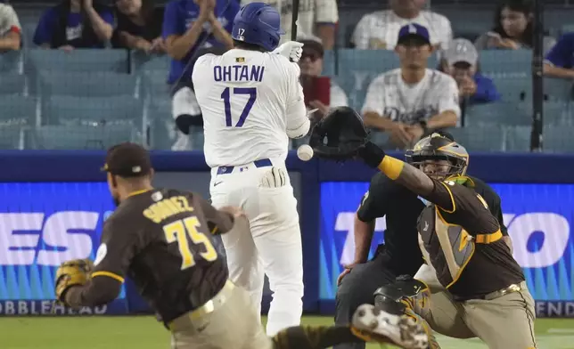 Los Angeles Dodgers' Shohei Ohtani, center is hit by a pitch thrown by San Diego Padres relief pitcher Robert Suarez, left as catcher Martin Maldonado watches during the ninth inning of a baseball game Thursday, June 19, 2025, in Los Angeles. (AP Photo/Mark J. Terrill)