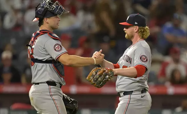 Washington Nationals catcher Riley Adams, left, shake hands with Nationals' relief pitcher Zach Brzykcy after the final out of the ninth inning of a baseball game against the Los Angeles Angels, Friday, June 27, 2025, in Anaheim, Calif. (AP Photo/Jayne Kamin-Oncea)