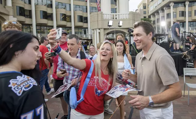 Washington Capitals forward T.J. Oshie, right, poses for a selfie with a fan after announcing his retirement from the NHL at Washington Harbour, Monday, June 9, 2025, in Washington. (AP Photo/Rod Lamkey, Jr.)