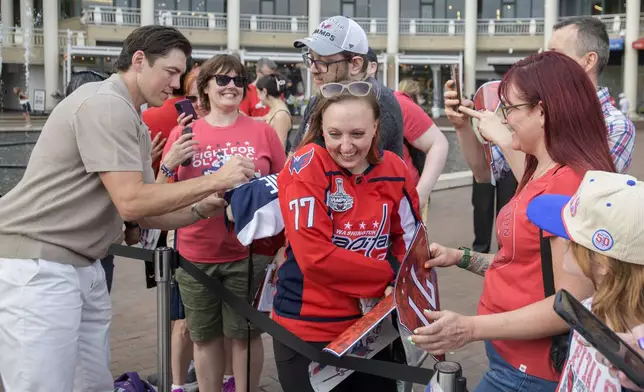 Washington Capitals forward T.J. Oshie, left, signs autographs for fans after announcing his retirement from the NHL at Washington Harbour, Monday, June 9, 2025, in Washington. (AP Photo/Rod Lamkey, Jr.)