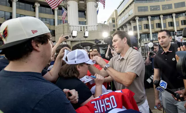 Washington Capitals forward T.J. Oshie, right, signs autographs for fans after announcing his retirement from the NHL at Washington Harbour, Monday, June 9, 2025, in Washington. (AP Photo/Rod Lamkey, Jr.)