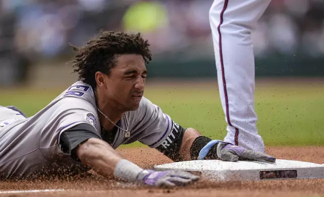 Colorado Rockies shortstop Ryan Ritter (8) slides into third base on errors after bunting against the Atlanta Braves in the third inning inning of a baseball game, Sunday, June 15, 2025, in Atlanta. (AP Photo/Mike Stewart)