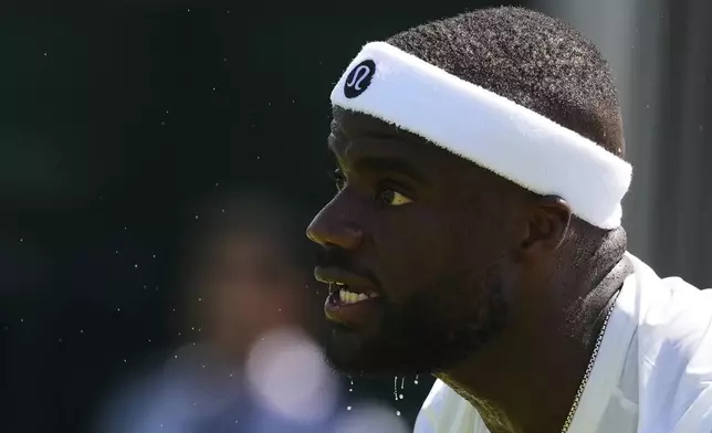 Frances Tiafoe of the U.S. rests as droplets of sweat drop off his chinb during his first round men's single match against Elmer Moller of Denmark at the Wimbledon Tennis Championships in London, Monday, June 30, 2025. (AP Photo/Kirsty Wigglesworth)