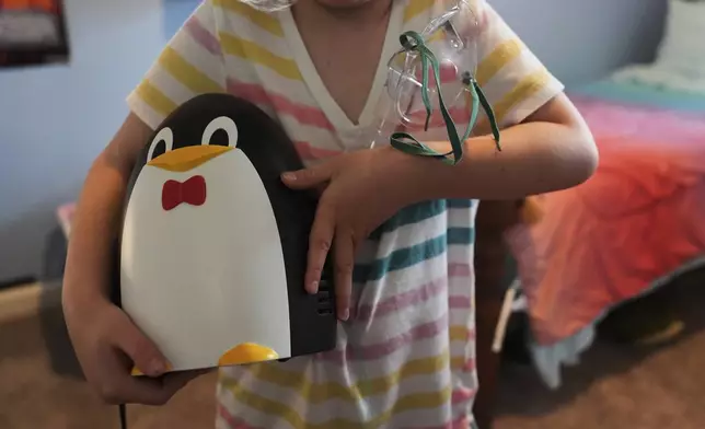 Eliza Ethridge, 5, holds her nebulizer Thursday, April 10, 2025, in Evansville, Ind. (AP Photo/Joshua A. Bickel)