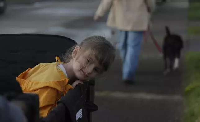 Eliza Ethridge, 5, rides in a wagon during a walk with her family, Thursday, April 10, 2025, in Evansville, Ind. (AP Photo/Joshua A. Bickel)