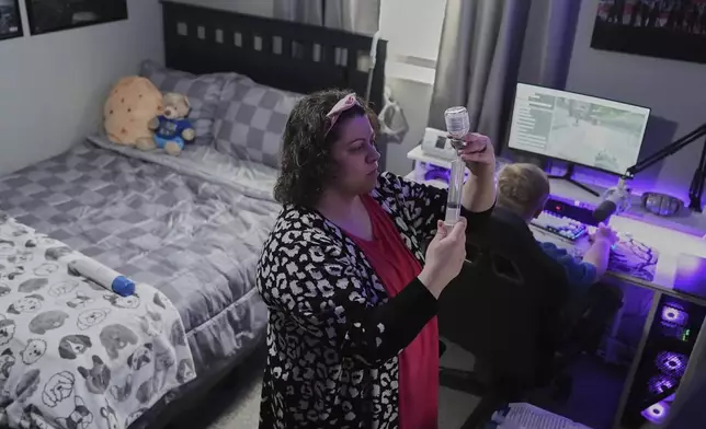 Jessica Blazier, center, prepares an infusion for her son, Julian, right, Wednesday, April 9, 2025, in Bloomfield, Ind. (AP Photo/Joshua A. Bickel)