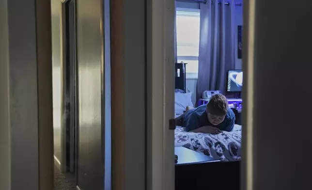 Julian Blazier relaxes in his bedroom Tuesday, April 8, 2025, in Bloomfield, Ind. (AP Photo/Joshua A. Bickel)