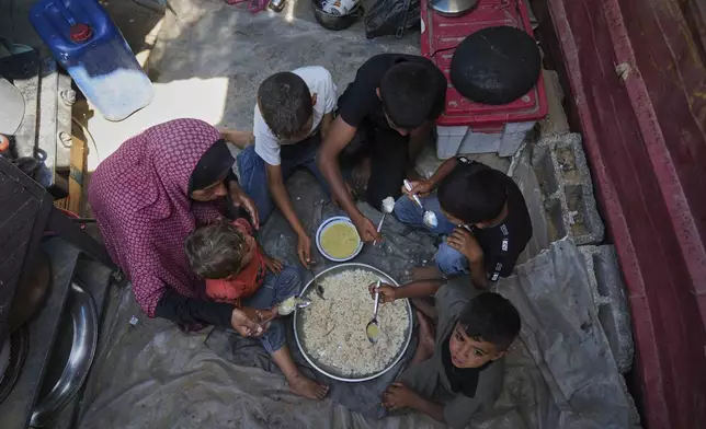 Tahreer Abu Jazar, 36, shares an Eid al-Adha meal of lentil soup and rice with her children inside their tent at a camp for displaced Palestinians in Mawasi Khan Younis, Gaza Strip, on Friday, June 6, 2025. (AP Photo/Abdel Kareem Hana)
