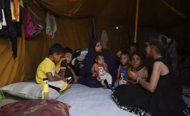 Maryam Abu Shaar, 29, sits with her children inside their tent at a camp for displaced Palestinians in Mawasi Khan Younis, Gaza Strip, on the first day of Eid al-Adha, Friday, June 6, 2025. (AP Photo/Abdel Kareem Hana)