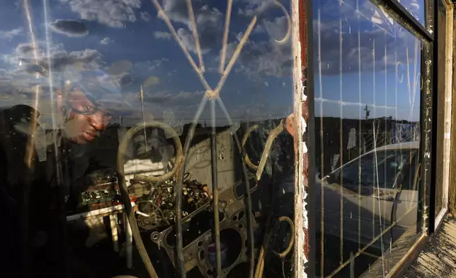 Themba Maseko, a 39-year-old mechanic, peeks through a window inside a workshop in Brakpan, east of Johannesburg, South Africa, Wednesday, April 30, 2025. (AP Photo/Themba Hadebe)