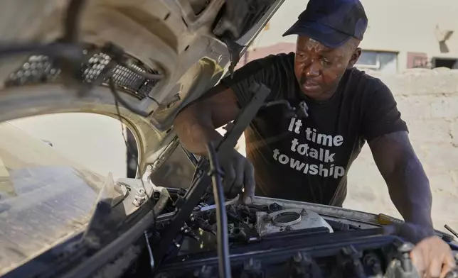 Themba Maseko, a 39-year-old mechanic, repairs a BMW car outside his workshop in Brakpan, east of Johannesburg, South Africa, Wednesday, May 14, 2025. (AP Photo/Themba Hadebe)