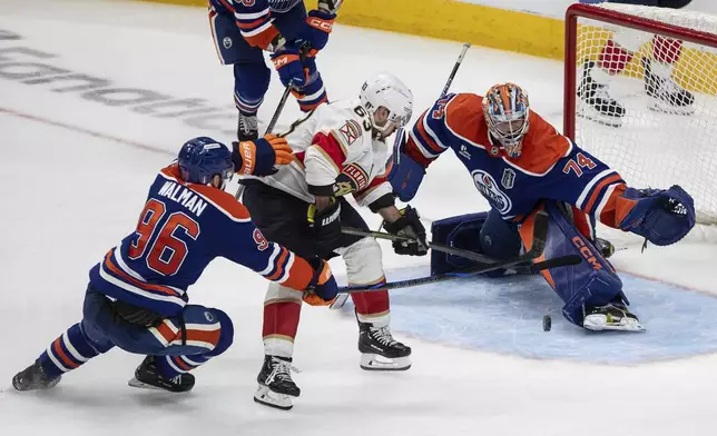 Florida Panthers' Brad Marchand (63) is stopped by Edmonton Oilers goalie Stuart Skinner (74) as Jake Walman (96) defends during the first overtime period in Game 2 of the NHL Stanley Cup final in Edmonton, Friday, June 6, 2025. (Jason Franson/The Canadian Press via AP)