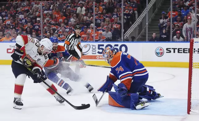 Florida Panthers' Brad Marchand (63) scores on Edmonton Oilers goalie Stuart Skinner (74) as Oilers' Leon Draisaitl, back right, defends during the second overtime period in Game 2 of the NHL Stanley Cup final in Edmonton, on Friday, June 6, 2025. (Darryl Dyck/The Canadian Press via AP)
