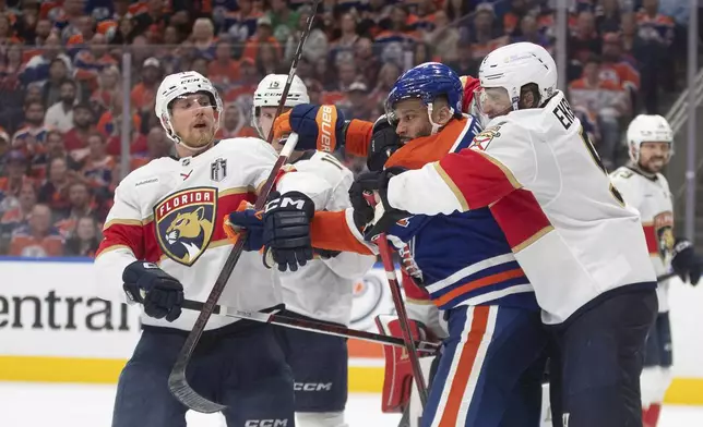 Florida Panthers' Aaron Ekblad (right) and Edmonton Oilers' Evander Kane (91) rough it up as Sam Reinhart (13) looks on during the first overtime period in Game 1 of the NHL Stanley Cup final in Edmonton, Alberta, Wednesday, June 4, 2025. (Jason Franson/The Canadian Press via AP)/The Canadian Press via AP)