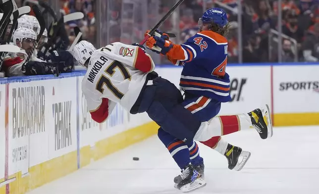 Edmonton Oilers' Kasperi Kapanen (42) checks Florida Panthers' Niko Mikkola (77) during the second period in Game 2 of the NHL hockey Stanley Cup Finals, in Edmonton, Alberta, Friday, June 6, 2025. (Darryl Dyck/The Canadian Press via AP)