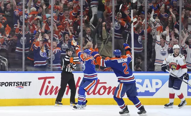 Edmonton Oilers' Corey Perry, back left, and Evan Bouchard (2) celebrates Perry's tying goal as Florida Panthers' Eetu Luostarinen (27) looks on during the third period in Game 2 of the NHL Stanley Cup Final, in Edmonton, on Friday, June 6, 2025. (Darryl Dyck/The Canadian Press via AP)