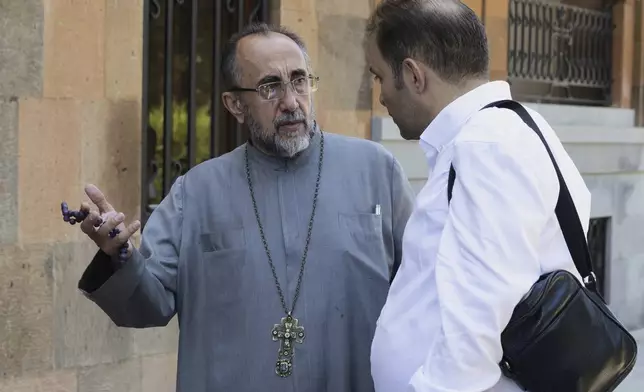 Mikael Ajapahyan, Archbishop of Gyumri and Shirak, left, speaks to a man as Armenian National Security Service officers arrive to arrest him, at Echmiadzin, the seat of the Armenian Apostolic Church outside Yerevan, Armenia, Friday, June 27, 2025. (Grigor Yepremyan, PAN Photo via AP)