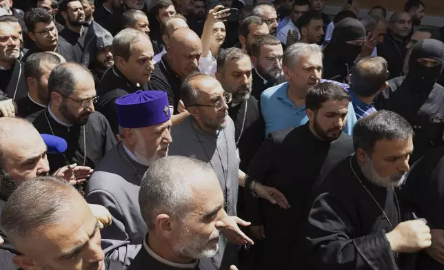Mikael Ajapahyan, Archbishop of Gyumri and Shirak, center, and Catholicos Karekin II, center left, walk surrounded by other priests as Armenian National Security Service officers arrive to arrest Ajapahyan, at Echmiadzin, the seat of the Armenian Apostolic Church outside Yerevan, Armenia, Friday, June 27, 2025. (Grigor Yepremyan, PAN Photo via AP)