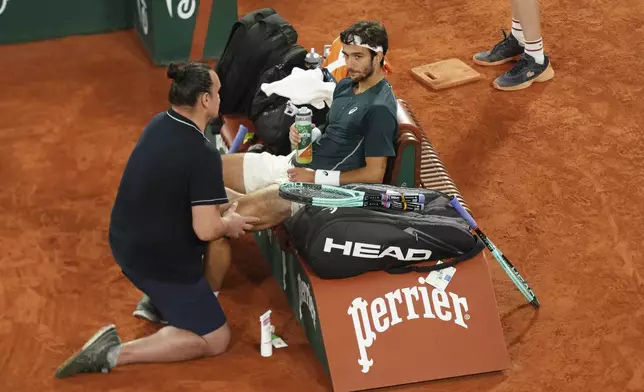 Italy's Lorenzo Musetti receives medical assistance during a break at the semifinal match of the French Tennis Open against Spain's Carlos Alcaraz at the Roland-Garros stadium in Paris, Friday, June 6, 2025. (AP Photo/Aurelien Morissard)