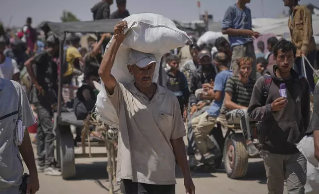 Palestinians carry food and humanitarian aid packages delivered by the Gaza Humanitarian Foundation, a U.S.-backed organization, in Rafah, southern Gaza Strip, Thursday, June 26, 2025. (AP Photo/Abdel Kareem Hana)