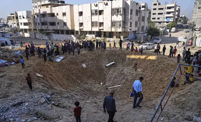 Palestinians gather around a crater caused by an Israeli strike on a displacement tent camp in Gaza City, June 28, 2025. (AP Photo/Jehad Alshrafi)