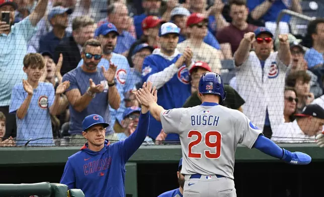 Chicago Cubs manager Craig Counsell, left, greets Michael Busch (29) after he scored a run on a sacrifice fly hit by Dansby Swanson against Washington Nationals pitcher Trevor Williams during the second inning of a baseball game in Washington, Tuesday, June 3, 2025. (AP Photo/Terrance Williams)